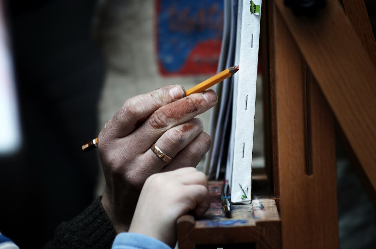 Close-up of an elderly hand guiding a child in drawing on canvas.