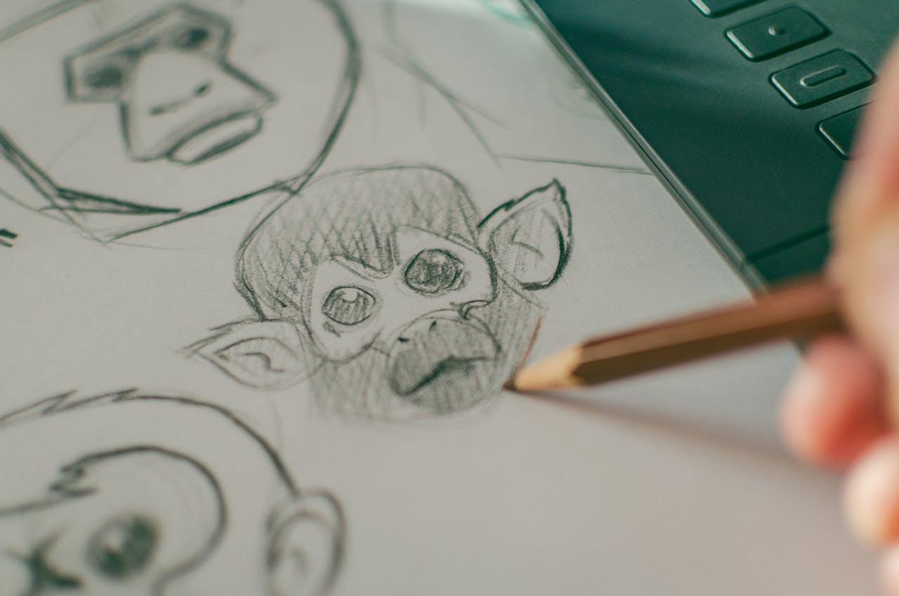 Close-up of hand sketching monkey faces on paper, showcasing artistic creativity.