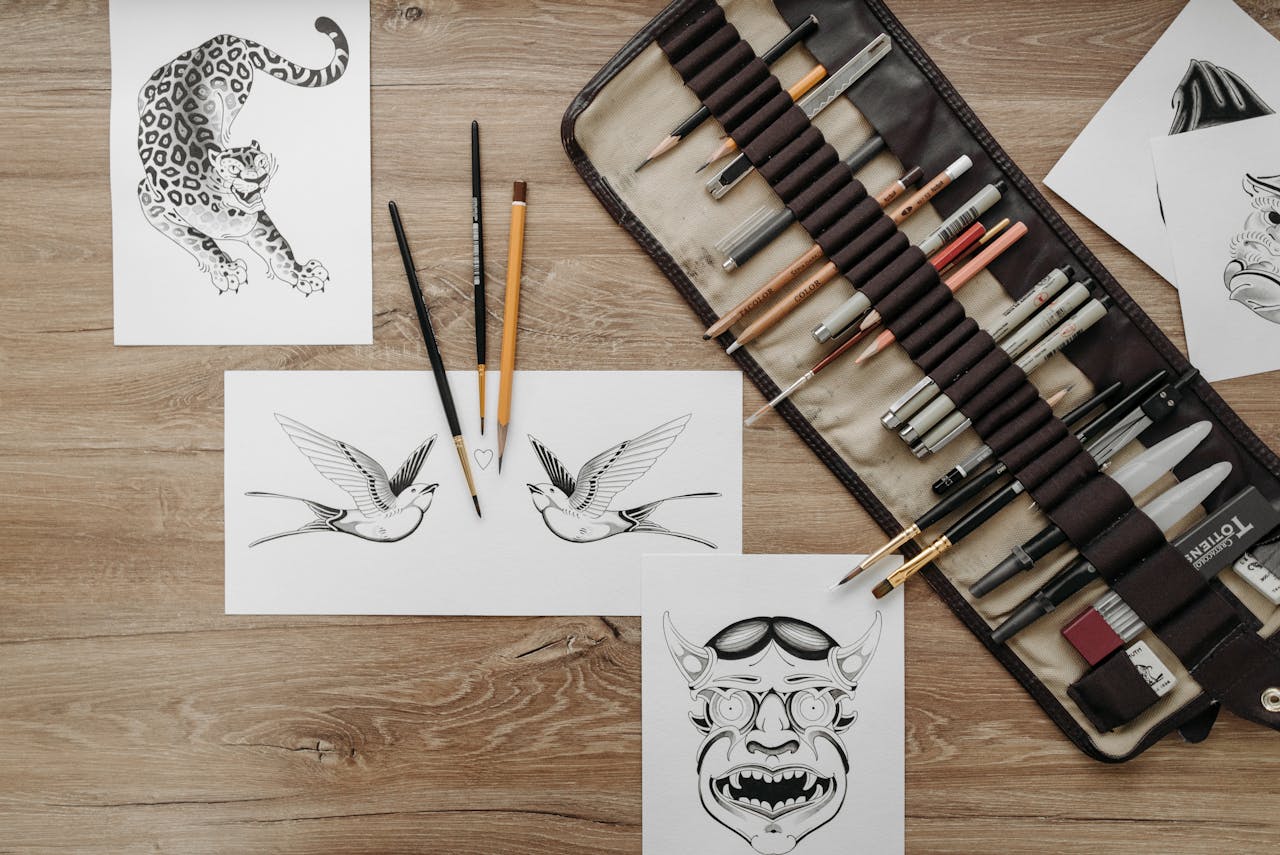 why-choose-us-02 Flat lay of tattoo design sketches and art supplies for artistic inspiration and creativity.