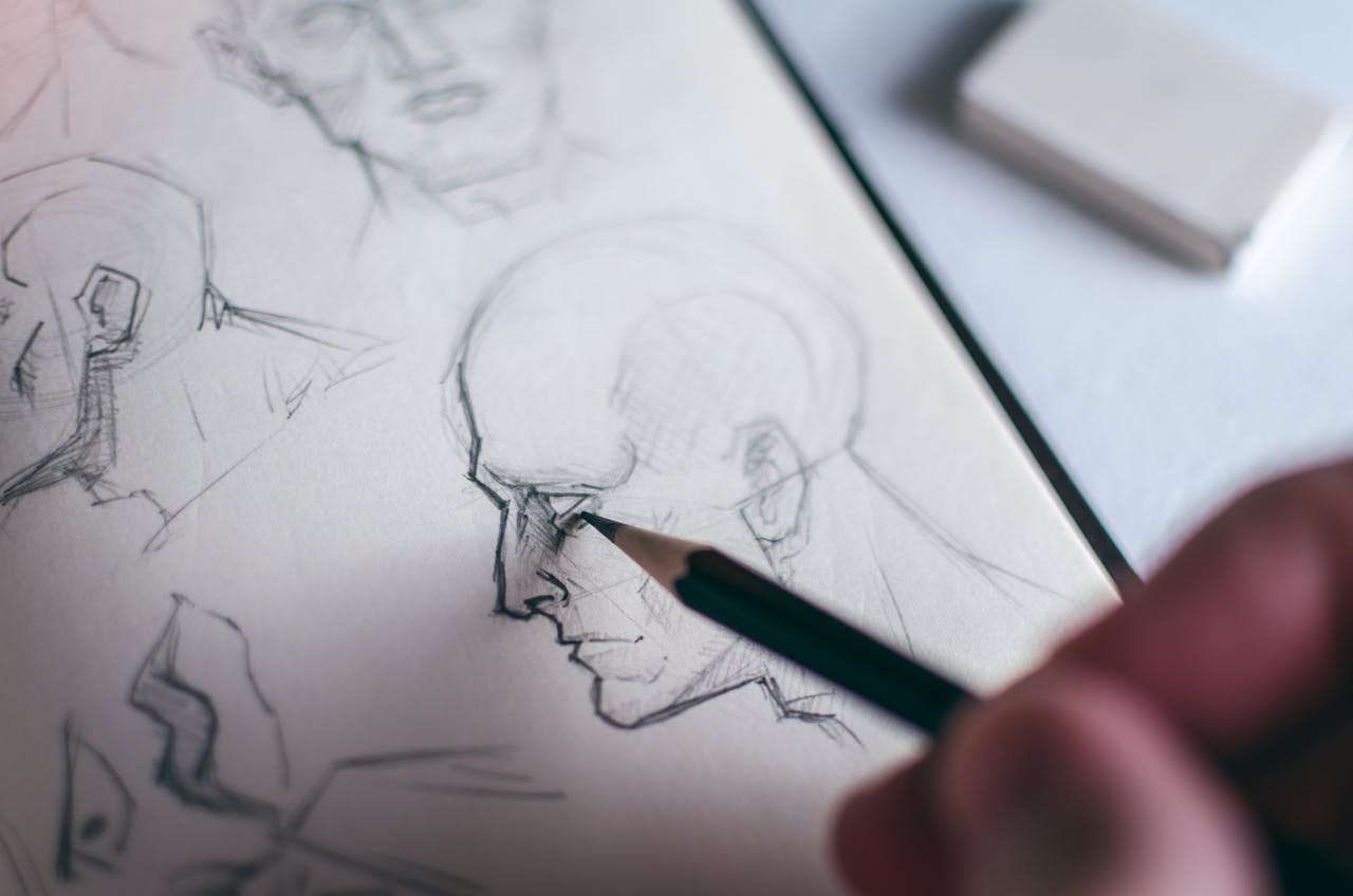 Detailed image of a hand sketching a human face in a sketchbook, emphasizing creativity.